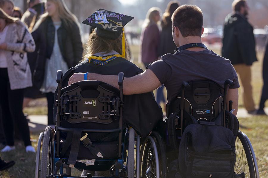 毕业典礼上，两个人坐在轮椅上，手挽着手.