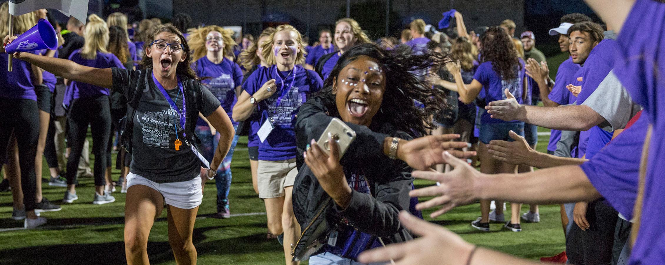  First-year students (freshman) & their peer mentors run through a human welcome tunnel of students & staff.